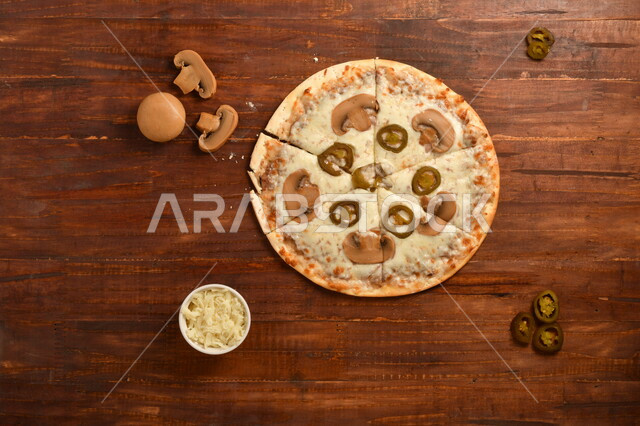 A delicious and delicious breakfast plate, a round pizza made of mushrooms and a lot of liquid cheese, many ingredients scattered next to the plate, delicious baked goods, a wooden surface