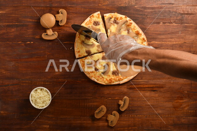 طبق فطور لذيذ و شهي  ، بيتزا دائرية الشكل مكونة من الفطر و الكثير من الجبنة السائلة ، مكونات عديدة متناثرة بجانب الطبق ، مخبوزات شهية ، سطح خشبي