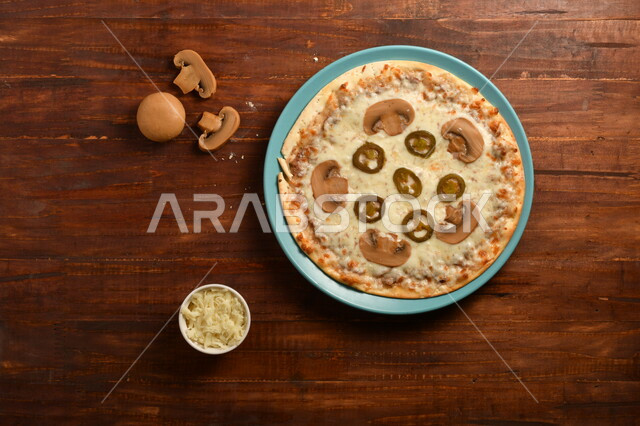 A delicious and delicious breakfast plate, a round pizza made of mushrooms and a lot of liquid cheese, many ingredients scattered next to the plate, delicious baked goods, a wooden surface