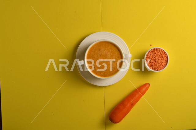 طبق مقبلات ساخنة لذيذ ، شوربة الجزر والعدس الصحية ، الشهية و اللذيذة ، مكونات الشوربة ( الجزر ، العدس )، خلفية صفراء