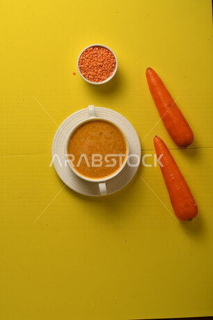 طبق مقبلات ساخنة لذيذ ، شوربة الجزر والعدس الصحية ، الشهية و اللذيذة ، مكونات الشوربة ( الجزر ، العدس )، خلفية صفراء