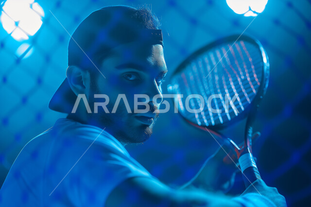  تعابير وإيماءات تدل على الجدية والحماس، الأنشطة الترفيهية والرياضات الشبابية، اتقان واحتراف الألعاب الرياضية الممتعة، لاعب بادل عربي خليجي سعودي يرتدي الزي الرياضي يقوم باللعب المضرب