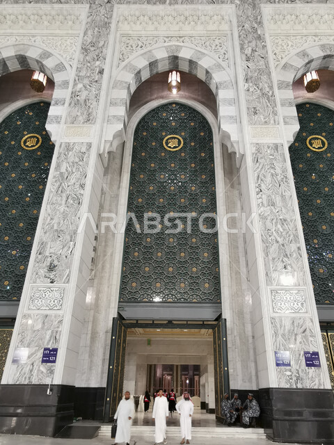 مجموعة من الحجاج والمعتمرين يقومون بدخول المسجد الحرام في مكة المكرمة، اداء مناسك الحج والعمرة، العبادة والتقرب إلى الله، معالم دينية اسلامية مقدسة في المملكة العربية السعودية