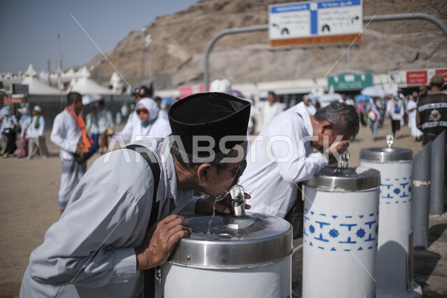 مقصد المسلمين من مختلف البلدان، موسم الحج في المملكة العربية السعودية، صورة مقربة لحاج يقوم بتعبئة المياه من أحد المبردات في أحد مناطق المشاعر المقدسة، توفير الماء للحجاج بشكل مستمر في الأجواء الحارة