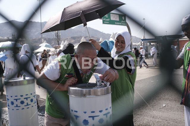 Providing water to pilgrims continuously in hot weather, a destination for Muslims from different countries, Hajj season in Saudi Arabia, close-up of a pilgrim filling water from a cooler in one of the holy sites areas