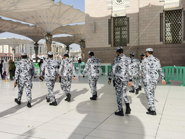 الحفاظ على سلامة وامان المسلمين اثناء اداء مناسك الحج والعمرة، جموعة من رجال الامن يمشون في ساحة المسجد النبوي الشريف في المدينة المنورة بالمملكة العربية السعودية، معالم دينية إسلامية