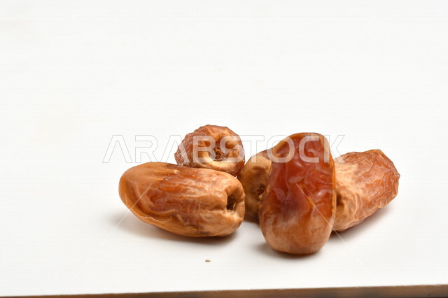 مجموعة من حبات التمر المليئة بالقيم الغذائية العالية ، فاكهه صيفية ، ثمار اشجار النخيل ، خلفية بيضاء