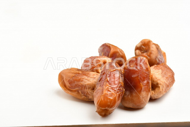 مجموعة من حبات التمر المليئة بالقيم الغذائية العالية ، فاكهه صيفية ، ثمار اشجار النخيل ، خلفية بيضاء