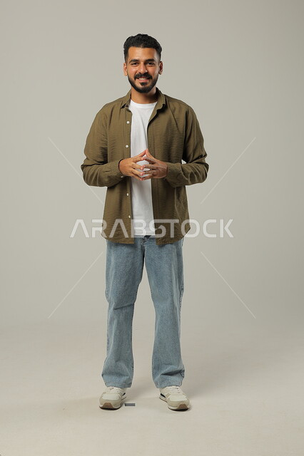 Meditation, thinking and planning for the future, gestures of thinking about something, portrait of a handsome young Arab Gulf Saudi man wearing casual clothes touching his fingertips with expressions of contemplation and concentration to find a solution to a problem, full body image, gray background