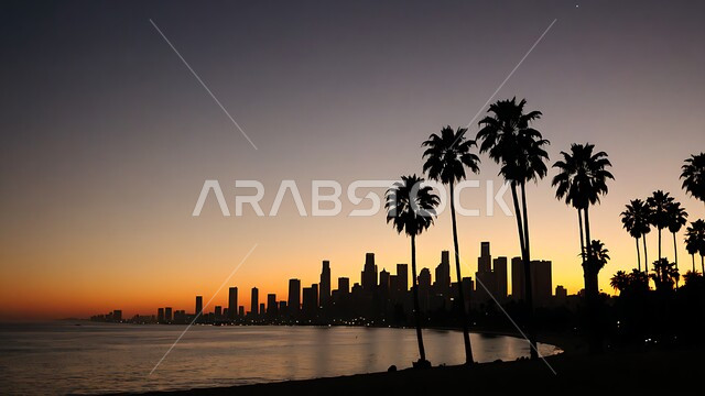A natural view of the beach at sunset, a silhouette of palm trees during sunset, a horizon of towers and skyscrapers, recreational tourist places in Saudi Arabia, calm sea waves