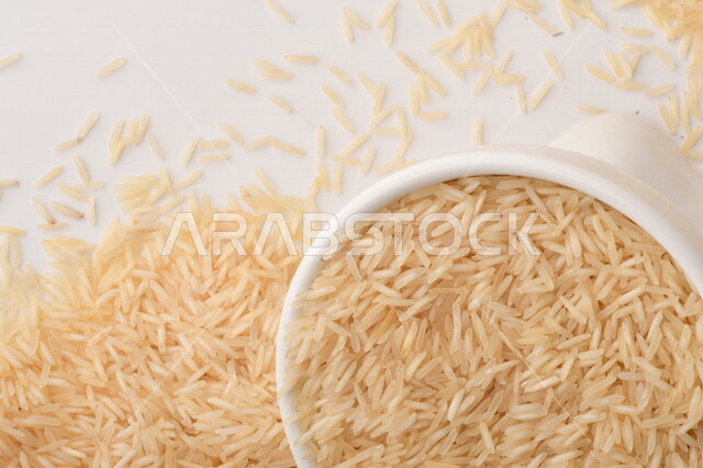 طبق أبيض مليء بحبيبات الرز ، الرز الابيض ،محصول الارز على خلفية بيضاء ، محاصيل زراعية