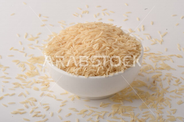 طبق أبيض مليء بحبيبات الرز ، الرز الابيض ،محصول الارز على خلفية بيضاء ، محاصيل زراعية