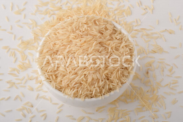 طبق أبيض مليء بحبيبات الرز ، الرز الابيض ،محصول الارز على خلفية بيضاء ، محاصيل زراعية