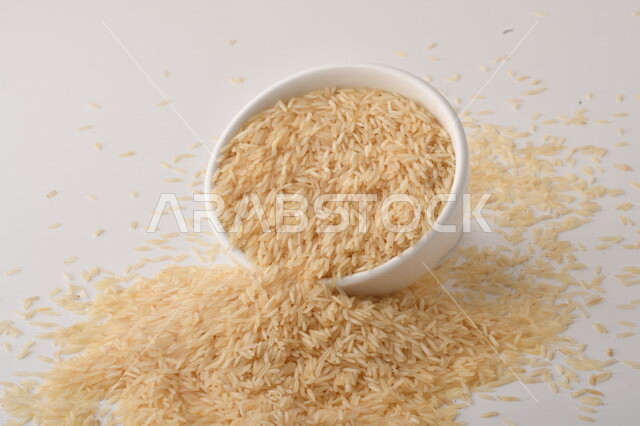 طبق أبيض مليء بحبيبات الرز ، الرز الابيض ،محصول الارز على خلفية بيضاء ، محاصيل زراعية