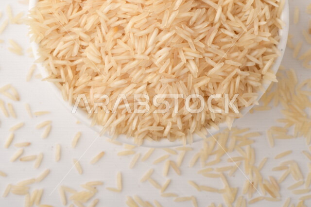 طبق أبيض مليء بحبيبات الرز ، الرز الابيض ،محصول الارز على خلفية بيضاء ، محاصيل زراعية