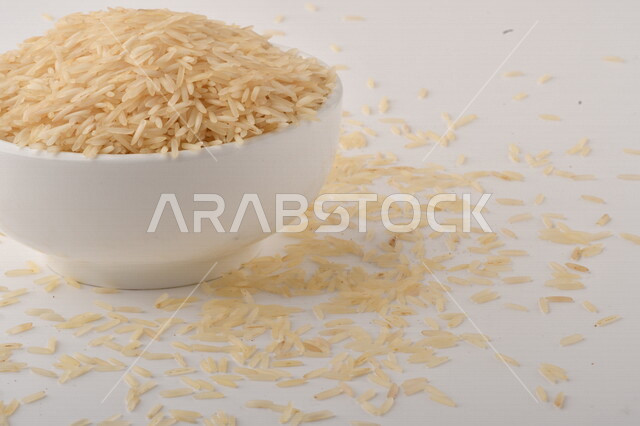 طبق أبيض مليء بحبيبات الرز ، الرز الابيض ،محصول الارز على خلفية بيضاء ، محاصيل زراعية