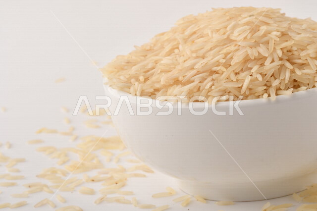 طبق أبيض مليء بحبيبات الرز ، الرز الابيض ،محصول الارز على خلفية بيضاء ، محاصيل زراعية