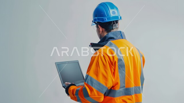 Working in the engineering sector, integrating work with technology, studying the basics of the project through modern applications and technologies, engineering project management, close-up portrait from the back of a Saudi Gulf Arab engineer wearing a helmet and protective vest holding a laptop in his hand, gray background