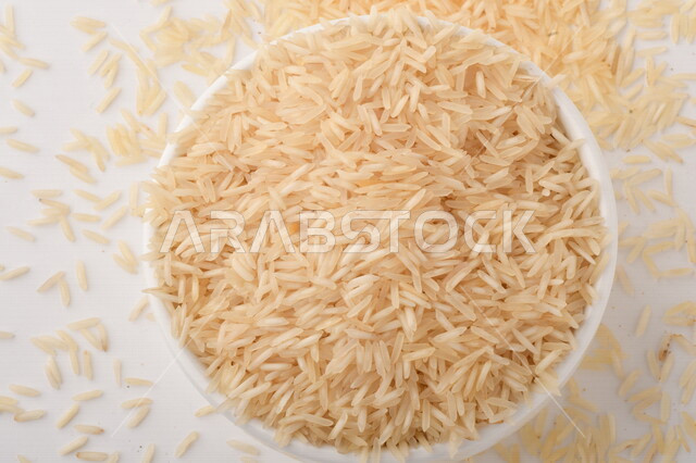 طبق أبيض مليء بحبيبات الرز ، الرز الابيض ،محصول الارز على خلفية بيضاء ، محاصيل زراعية