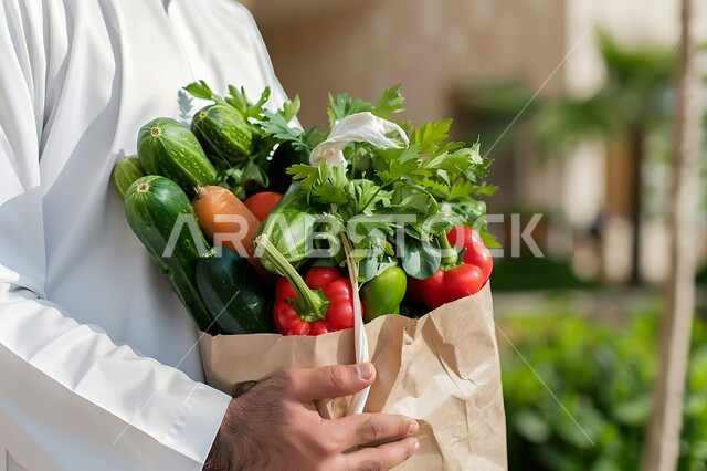 المحاصيل الزراعية السعودية ذات الجودة العالية، انتقاء أجود أنواع الخضراوات الطازجة، صورة مقربة لرجل عربي خليجي سعودي يحمل بيده كيس ورقي مليء بالخضار، وجبة طعام صحية خفيفة، تلبية الحاجات الضرورية للجسم