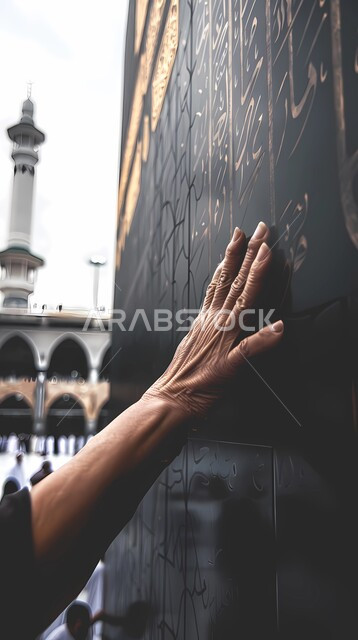 Worship, duties and drawing closer to God, the importance of religious sanctities for Muslims, the hand of a pilgrim or Umrah performer extending to touch the wall of the Kaaba in the Grand Mosque in Mecca, performing the Hajj and Umrah rituals, Islamic religious landmarks in Mecca in the Kingdom of Saudi Arabia