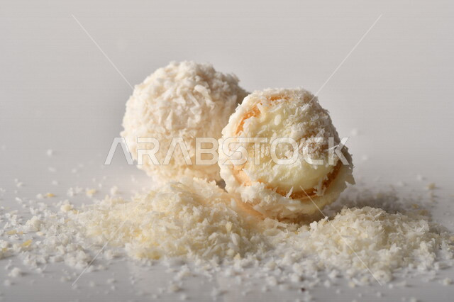 كرات حلوى الشوكولاته البيضاء مُكونة من اللوز والجوز الهند , صورة مقربة لحلوى متشققة مع رقائق اللوز وجوز الهند اللذيذة على طاولة سوداء