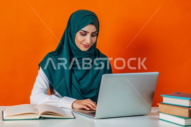 جودة التعليم وتطور الوسائل التعليمية في المملكة العربية السعودية، إستخدام الأجهزة التقنية الحديثة، مفهوم التعليم و العمل عن بعد، بورتريه مقرب لفتاة عربية خليجية سعودية محجبة مبتسمة تعمل على جهاز الحاسوب المحمول، خلفية برتقالية
