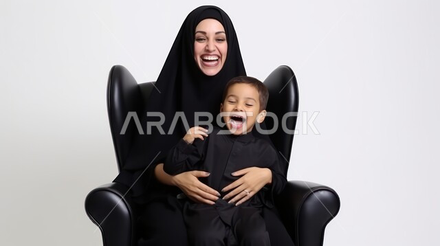  إيماءات السعادة والسرور، تعزيز رابط الأمومة بين الأم وصغيرها،مفهوم حنان الأمهات و تحمل المسؤولية والعناية بالأطفال، بورتريه مقرب لسيدة عربية خليجية سعودية محجبة تحمل طفلها وتلهو معه، الشعور بالأمان والاطمئنان، خلفية بيضاء