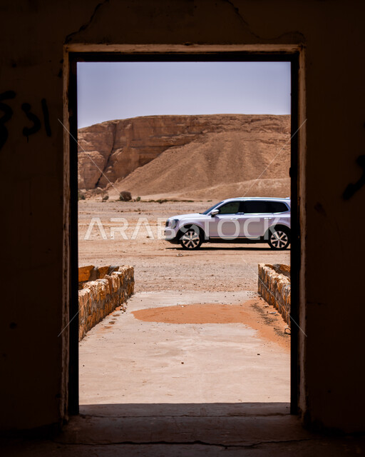 سيارة دفع رباعي بيضاء، صورة من داخل منزل تراثي قديم لبوابة مطلة على الرمال، المناطق الطبيعية الصحراوية في المملكة العربية، أماكن ومعالم اثرية سياحية في السعودية