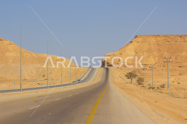 Asphalt travel road between sand dunes, a highway in the middle of the desert in the Kingdom of Saudi Arabia, preparing highway infrastructure in the desert nature