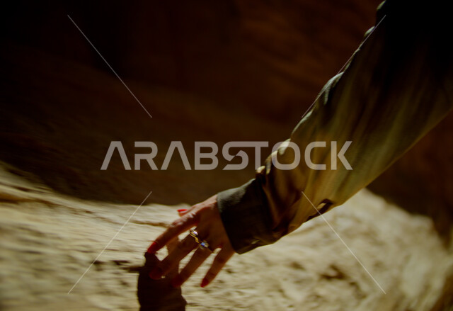 Adventure and fun tourist places, rock formations and formations in the desert, desert environment in the Kingdom of Saudi Arabia, close-up of a Saudi Arabian Gulf woman's hand wearing a scarf touching rocks and historical monuments, enjoying spending time on vacation