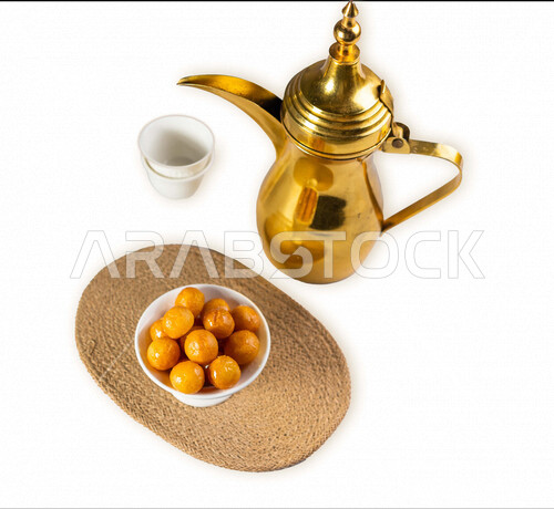 بورتريه دلة قهوه عربية مع طبق من الحلويات اللذيذ ، طبق لقيمات شهية ، الضيافة الرمضانية ، خلفية بيضاء