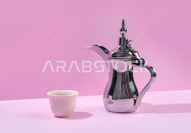 مفهوم حسن استقبال الضيف وإكرامه, بورتريه لدلة فضية من القهوة العربية الفاخرة مع الفنجان, تقديم مشروب البن الساخن للزوار, العادات الأصيلة المتوارثة عند العرب, خلفية وردية