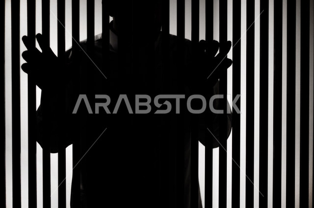 رجل عربي خليجي سعودي داخل السجن ، يمسك القضبان الحديدية ، سجين سعودي ينتظر الحرية ، الشعور بالندم والوحدة 