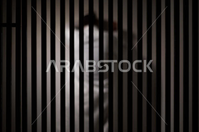 رجل عربي خليجي سعودي خلف القضبان الحديدية ، رجل سعودي يضع راسه على الحائط ، الشعور بالندم والوحدة ، ينتظرالحرية 