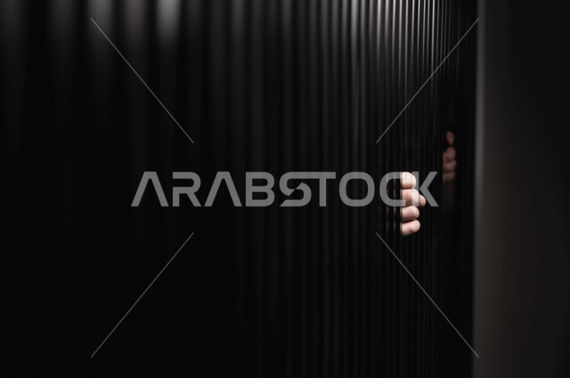 تصوير مقرب ليد سجين عربي خليجي سعودي يمسك القضبان الحديدية ، رجل سعودي داخل السجن ، سجين ينتظر الحرية ، الشعور بالندم والوحدة 