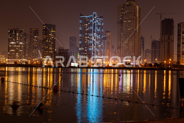 الفن الهندسي المعماري في بناء الأبراج وناطحات السحاب على شاطئ الممزر, الواجهة البحرية الساحلية في مدينة دبي, النمو والتطور العمراني في الامارات العربية المتحدة, وجهات جذب واستقطاب السياح, انعكاس الأضواء والأنوار للفنادق والمباني على مياه البحر في وقت الليل