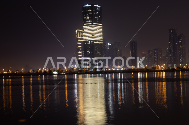 Dubai's coastal waterfront, architectural art in building towers and skyscrapers on Al Mamzar Beach, urban growth and development in the United Arab Emirates, tourist attractions and attraction, reflection of lights and lights of hotels and buildings on the sea water at night