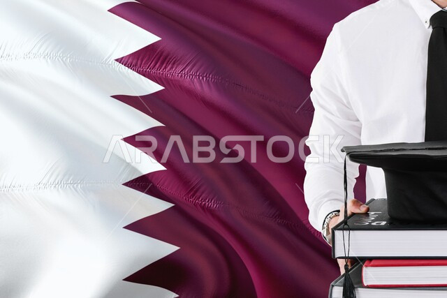 مفهوم الاجتهاد والتفوق، الاحتفال بانهاء الدراسة الجامعية، الفخر والثقة بتحقيق حلم النجاح، صورة مقربة لطالب يرتدي القميص الابيض يحمل مجموعة من الكتب مع قبعة التخرج، التعليم الأكاديمي في دولة قطر
