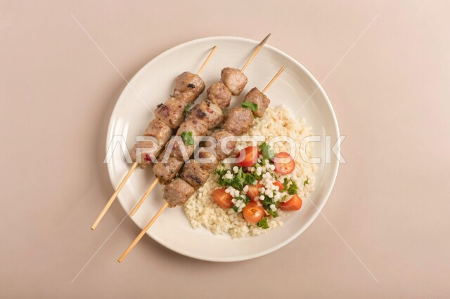 أطباق ووصفات المتميزة، قطع لحم الضأن المشوية المرتبة على طبق مع سلطة الكسكس الشهية، مطاعم للمأكولات الشرقية في المملكة العربية السعودية، وجبات اللحم الصحية والمغذية، خلفية بيج