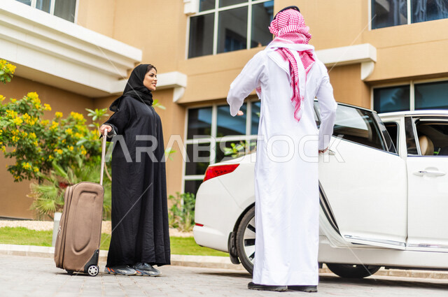 رجل عربي خليجي سعودي يوقف سيارته امام الفندق ، يفتح باب السيارة لامرأة عربية خليجية سعودية محجبة ، تحمل بيدها حقيبة سفر ، خدمة توصيل الركاب ، راحة وأمان 