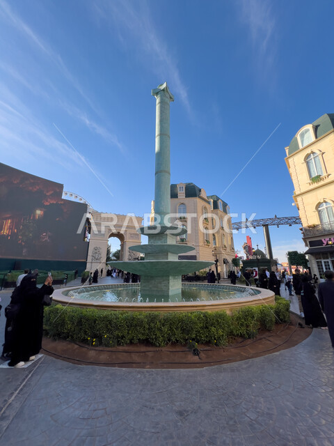 الاستمتاع بالتجارب الممتعة في أبرز المناطق الترفيهية بالمملكة العربية السعودية، معالم جذب واستقطاب السائحين، القرية الفرنسية في البوليفارد ورلد في مدينة الرياض، الفن الهندسي المعماري على الطراز الحديث، صورة بركة مياه مزينة بالاعشاب وسط الساحة