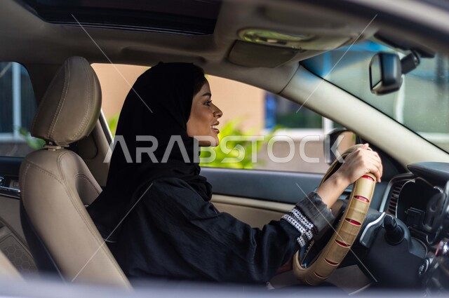 امرأة عربية خليجية سعودية محجبة ، تقود السيارة بمتعة وسعادة ، حرية القيادة للمرأة العربية السعودية ، خدمة توصيل الركاب ، راحة وامان 