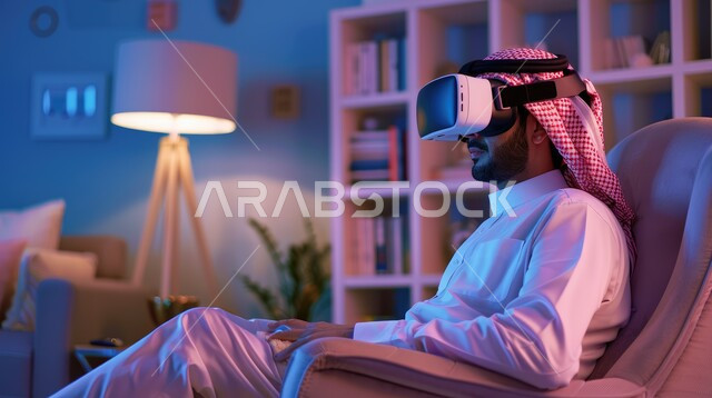تعابير التركيز والاندماج، محاكاة العالم الخيالي، صورة مقربة لرجل عربي خليجي سعودي يرتدي الثوب التقليدي والشماغ يجلس على اريكة مريحة يقوم بمشاهدة الأفلام عبر نظارة الواقع الإفتراضي، الأجهزة والتقنيات الحديثة والمتطورة، لعب ألعاب الفيديو ثلاثية الأبعاد