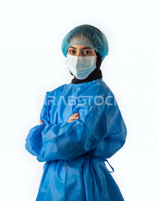 بورتريه لطبيبة عربية سعودية مسلمة محجبة ترتدي زي العمليات متقاطعة اليدين بإيماءات وجه ويدين مختلفة ، ترتدي رداء أزرق قماشي ، ترتدي كمامة الوجه ، تجنب انتشار العدوى ، مفهوم الطب ، خلفية بيضاء