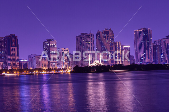 Architectural engineering art of towers and skyscrapers illuminated at night overlooking the Arabian Gulf, view of Al Majaz Waterfront, Al Khan Lake Corniche in Sharjah, United Arab Emirates, famous landmarks and tourist places