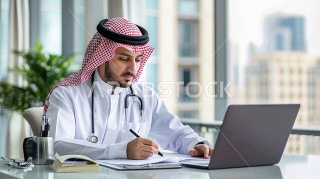 طبيب عربي خليجي سعودي يجلس امام الحاسوب المحمول ويقوم بالكتابة على الورق، اعداد التقرير الطبي, وصف ودراسة الحالة المرضية، تقديم الخدمات الصحية، مفهوم الطب والرعاية الصحية