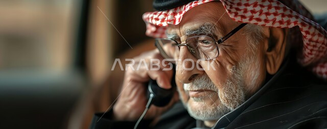 الاتفاق مع الأصدقاء عبر برامج التواصل الاجتماعي، دردشات ومحادثات عبر الانترنت، صورة مقربة لرجل كبير السن عربي خليجي سعودي يرتدي الشماغ والثوب التقليدي يستخدم الهاتف المحمول يمسك بيده العكازة، إجراء مكالمات صوتية بإيماءات التفكير واليأس