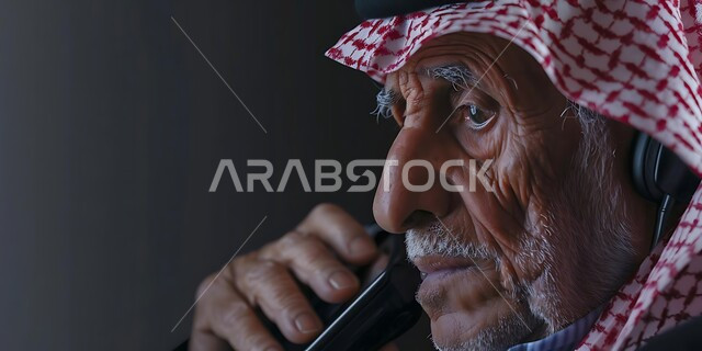 التحدث مع الأصدقاء عبر برامج التواصل الاجتماعي، دردشات ومحادثات عبر الانترنت، صورة مقربة لرجل كبير السن عربي خليجي سعودي يرتدي الشماغ والثوب التقليدي يستخدم الهاتف المحمول، إجراء مكالمات صوتية بإيماءات الجزن واليأس