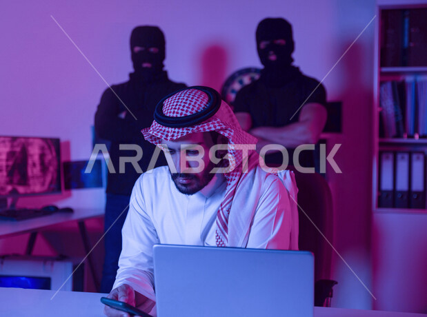 A Saudi Arabian Gulf man sitting in front of a laptop, using a mobile phone, masked men standing behind, planning cyber attacks, cyber attack, data theft, cyber security